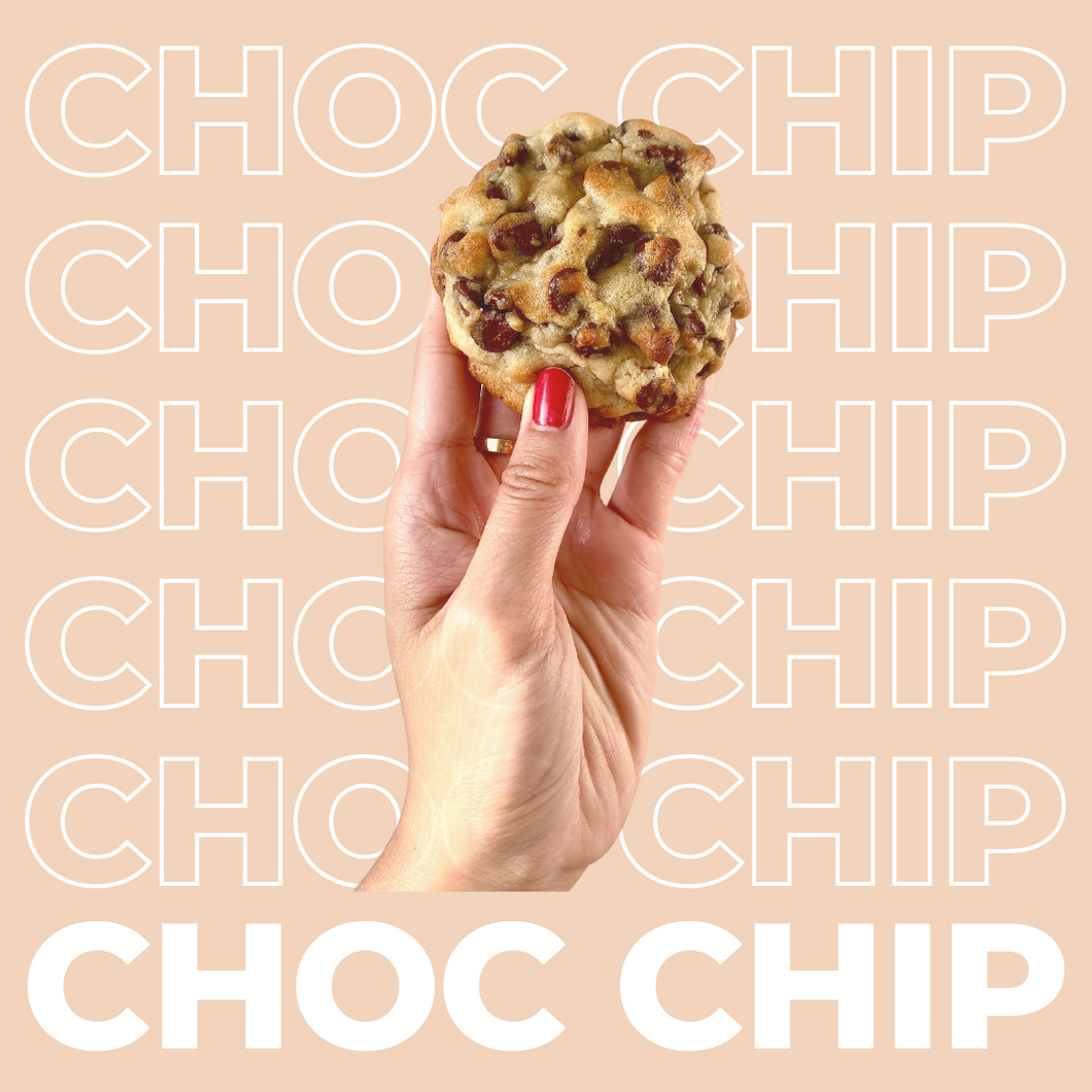 The Chocolate Chip Cookie being held up by model's hand.