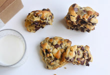 Load image into Gallery viewer, Multiple textured chocolate chip cookies placed next to a glass of milk.
