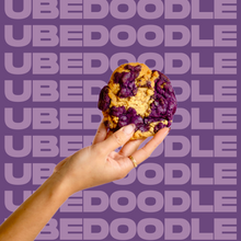 Load image into Gallery viewer, The Ubedoodle Cookie being held up by model&#39;s hand.
